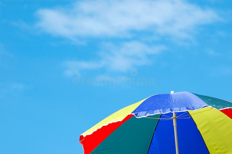 A colorful open beach umbrella for summer sunshade. This parasol is standing in front of blue sky with some clouds. A colorful open beach umbrella for summer sunshade. This parasol is standing in front of blue sky with some clouds