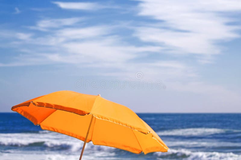 An umbrella on the beach over the ocean horizon and a cloudy sky. An umbrella on the beach over the ocean horizon and a cloudy sky