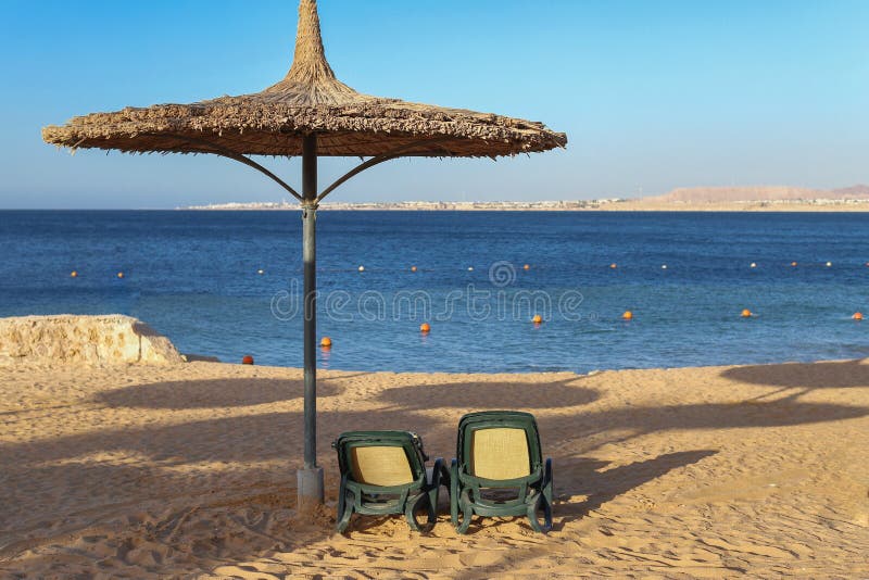 Parasol en sunbeds op het strand aan het rietoverzees stock afbeeldingen Parasol en sunbeds op het strand aan het rietoverzees stock afbeeldingen