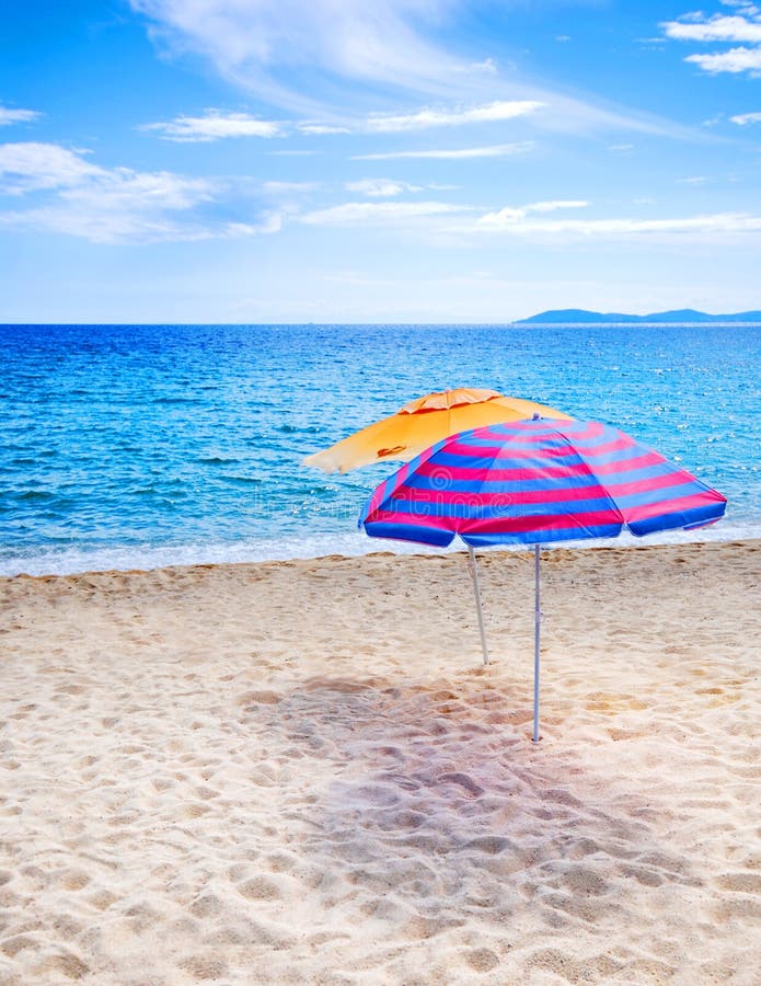 Two beach umbrellas on empty beach and bright blue ocean. Two beach umbrellas on empty beach and bright blue ocean.