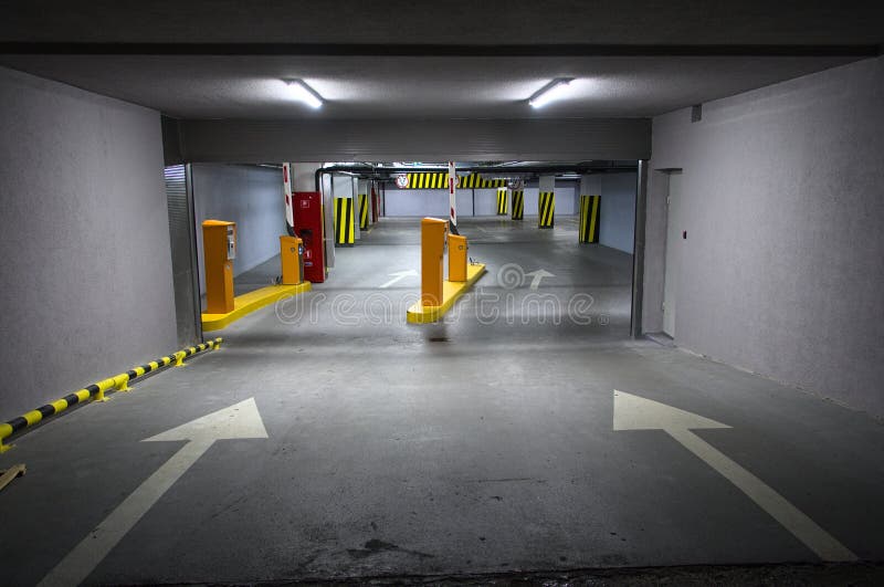 Parcheggio sotterraneo con le frecce ed un'automobile parcheggiata immagine stock Parcheggio sotterraneo con le frecce ed un'automobile parcheggiata immagine stock