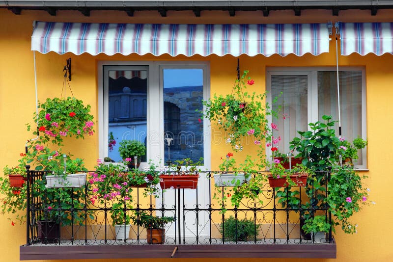 Pared amarilla del edificio con el jardín florido del balcón