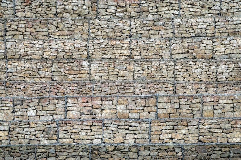 Pared de Gabion de rocas y de piedras en caja del alambre de metal Cerca de piedras en la rejilla Pared de piedra protectora en l imágenes de archivo libres de regalías Pared de Gabion de rocas y de piedras en caja del alambre de metal Cerca de piedras en la rejilla Pared de piedra protectora en l imágenes de archivo libres de regalías