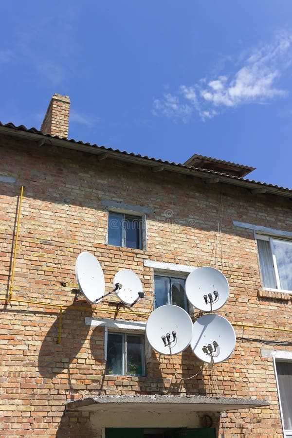 Parede da casa do tijolo vermelho com as antenas da placa da antena parabólica fotografia de stock Parede da casa do tijolo vermelho com as antenas da placa da antena parabólica fotografia de stock