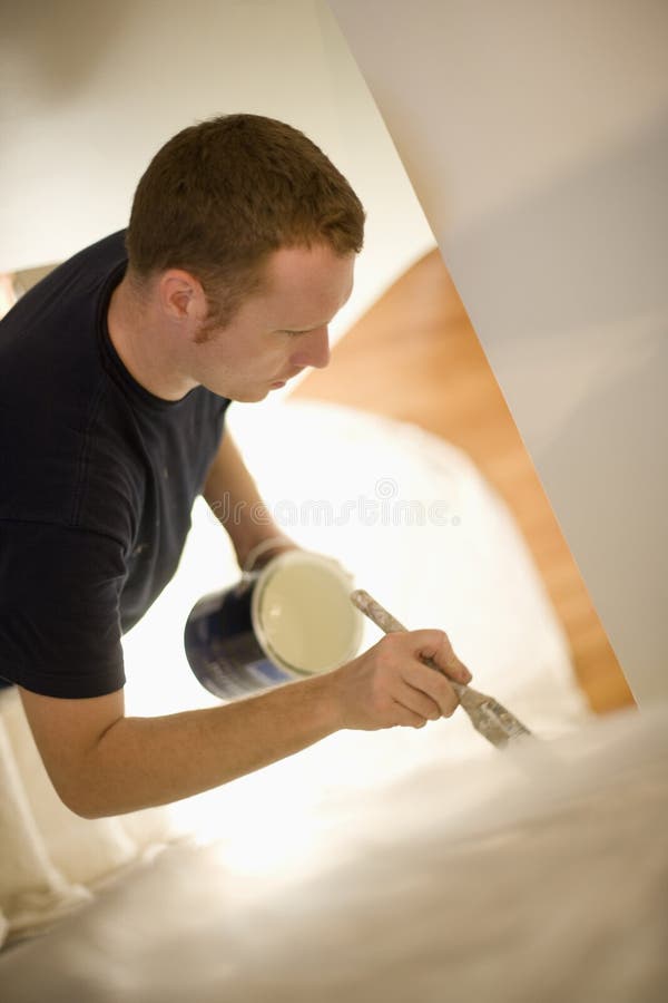 Young man concentrates painting stairway walls. Young man concentrates painting stairway walls