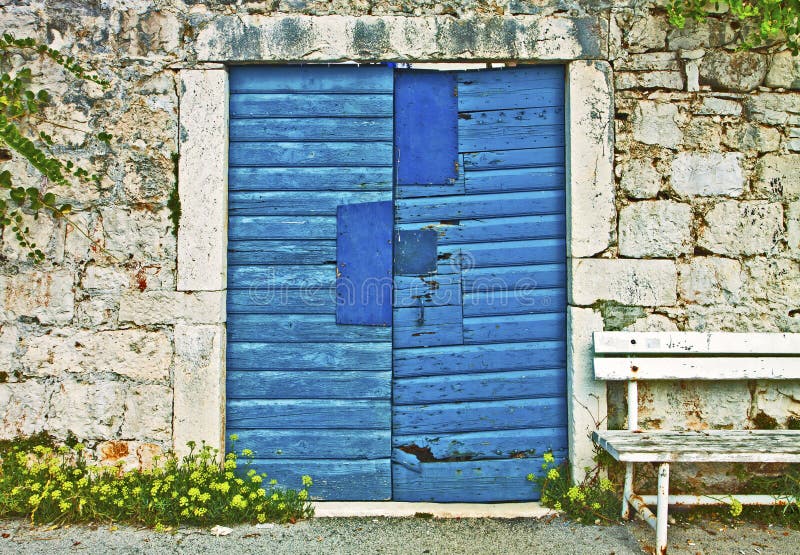 Parede de pedra, porta azul do vintage e banco de madeira fotografia de stock royalty free Parede de pedra, porta azul do vintage e banco de madeira fotografia de stock royalty free