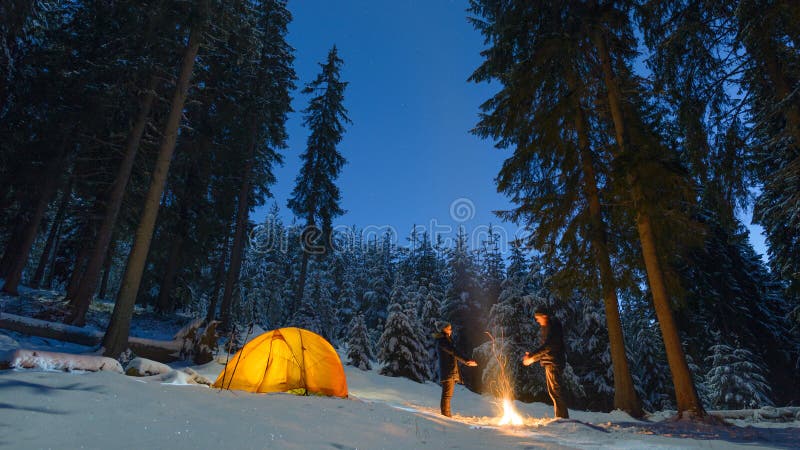 Pareja acampar con fogata y carpa al aire libre en el bosque invernal fotografía de archivo