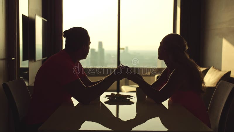 Pareja amante de la silueta sentada en la mesa de la cocina moderna. vista de ciudad de ventana. hombre de relación y mujer