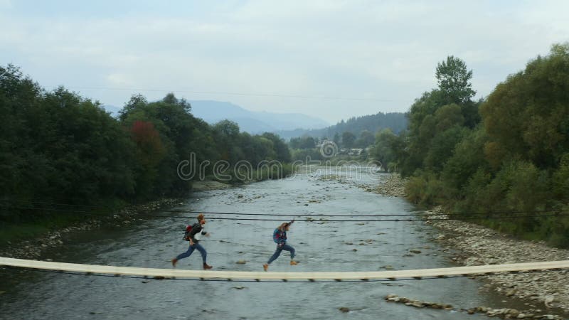 Pareja aérea de puente de naturaleza corriendo para divertirse cerca del pequeño río de montaña almacen de metraje de vídeo