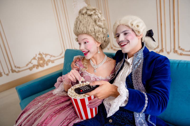 Pareja Baroquecostumed disfrutando del tiempo libre en casa con aperitivos y entretenimiento que resaltan la elegancia y el clasic fotografía de archivo