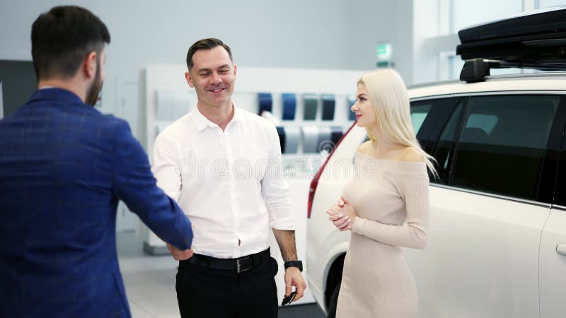 Pareja de jóvenes casados se felicitan por el abrazo de un vendedor de autos almacen de video