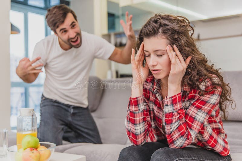 Pareja de matrimonios que se sienta en Gray Bed y la discusión Retrato de los gritos enojados del marido en la esposa decepcionad fotografía de archivo Pareja de matrimonios que se sienta en Gray Bed y la discusión Retrato de los gritos enojados del marido en la esposa decepcionad fotografía de archivo