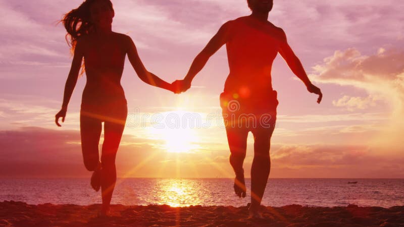 Pareja de playa romántica con puesta de sol en la playa corriendo divirtiéndose en el viaje