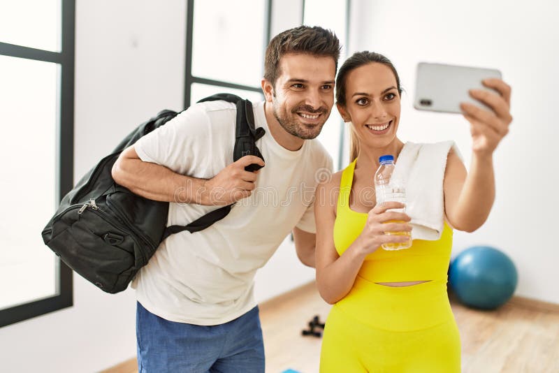 Pareja deportiva hispana joven haciendo selfie con el smartphone del centro deportivo foto de archivo