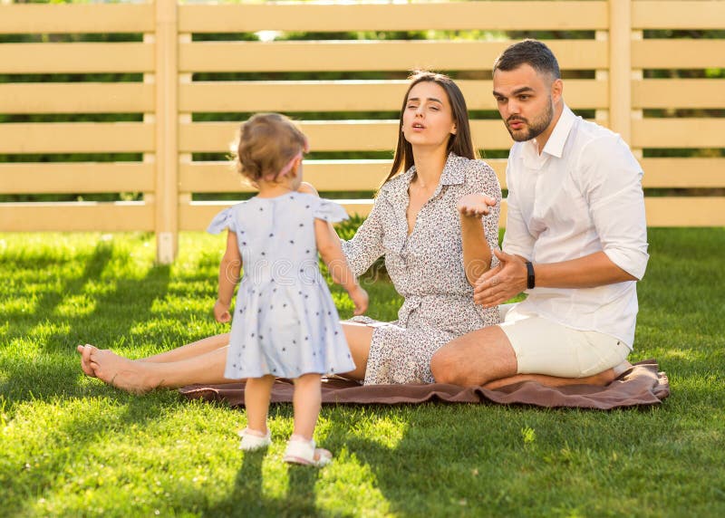 Pareja en amor con la pequeña hija en una comida campestre cerca de su hogar, fotografía de archivo Pareja en amor con la pequeña hija en una comida campestre cerca de su hogar, fotografía de archivo