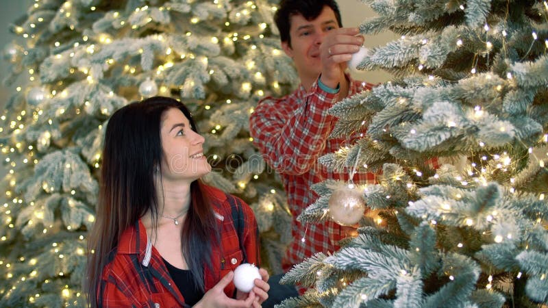 Pareja encantadora decora el árbol de navidad