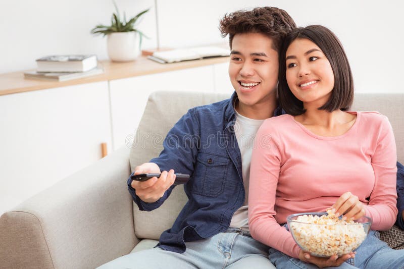 Pareja familiar china observa canales de conmutación de TV sentados en casa imagen de archivo