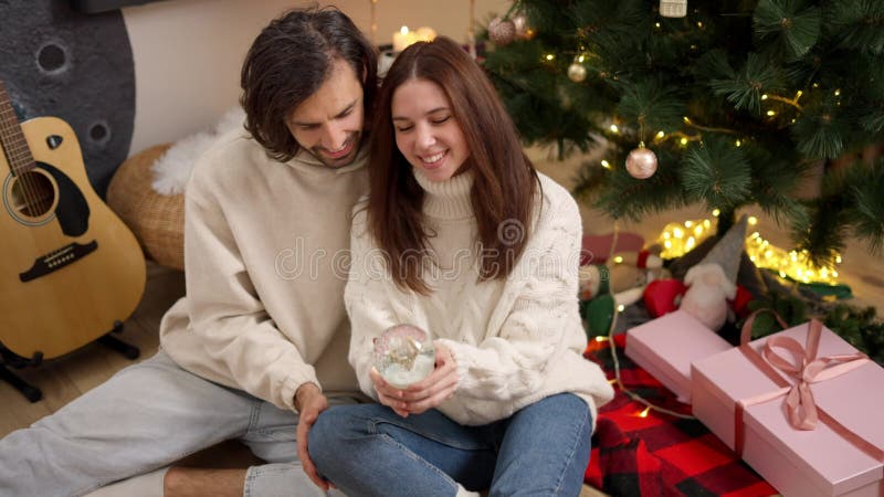 Pareja feliz un tipo de morena con una sudadera blanca y una morena con un suéter blanco que sacude los años nuevos almacen de metraje de vídeo