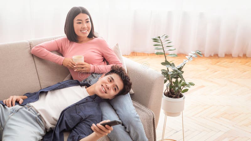 Pareja japonesa viendo televisión disfrutando de películas familiares relajándose en casa imagenes de archivo