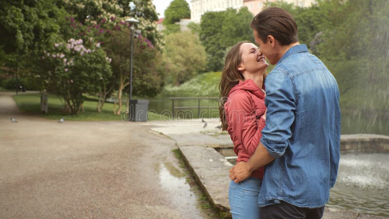 Pareja joven y feliz que tiene citas en el parque cerca de una fuente. relaciones amistad y amor.