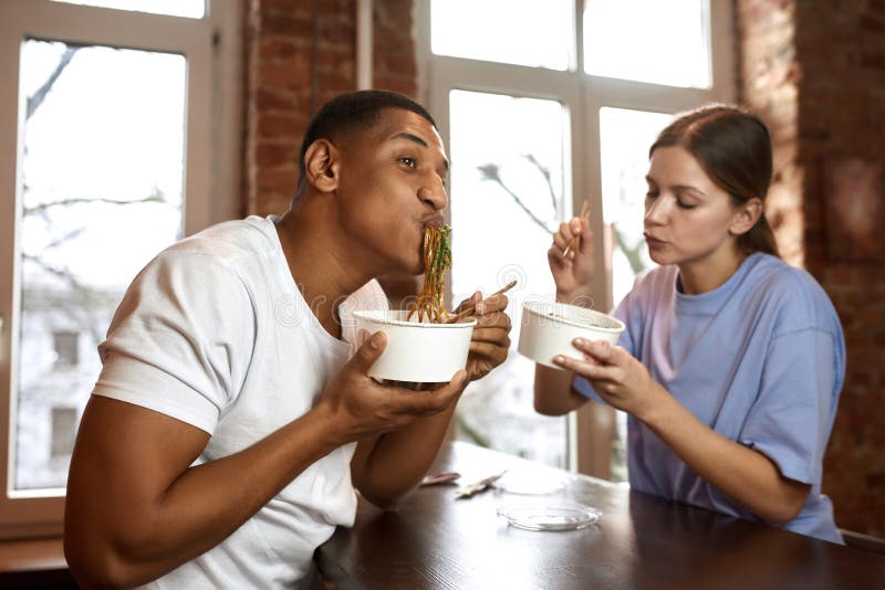 Pareja multirracial come fideos en desafío de video foto de archivo libre de regalías