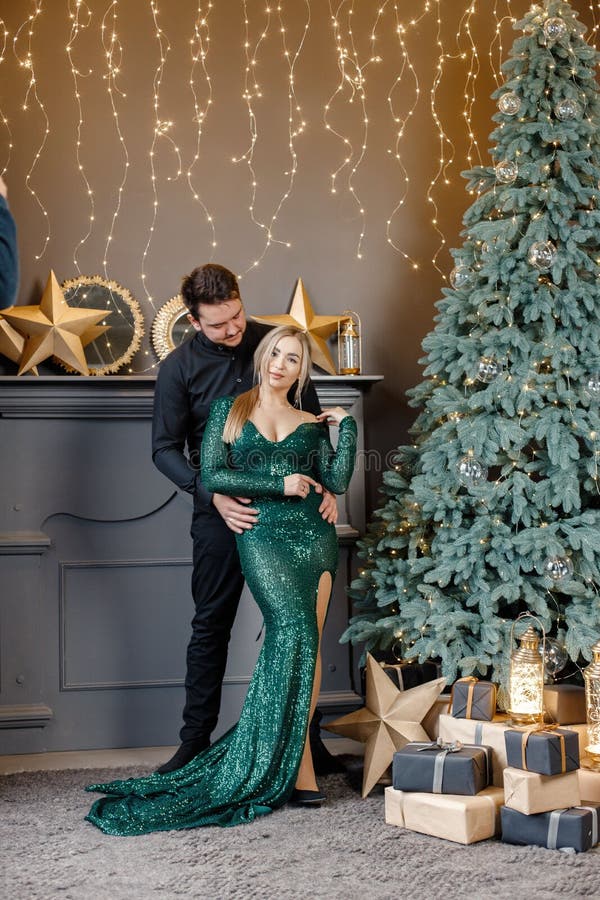 Hermosa pareja elegante feliz de moda en ropa de moda con capucha y camisa  cerca del árbol de navidad en casa