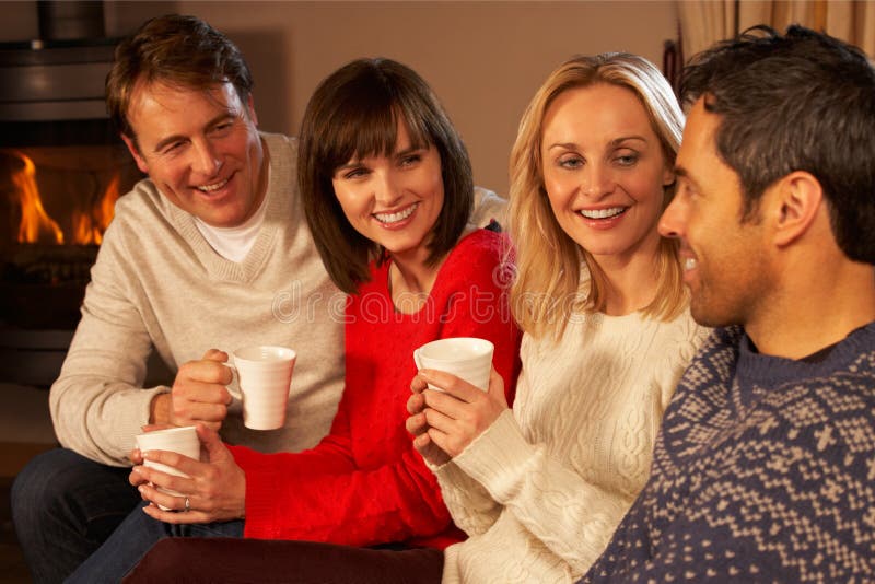 Group Of Middle Aged Couples Sitting On Sofa With Hot Drinks Talking. Group Of Middle Aged Couples Sitting On Sofa With Hot Drinks Talking