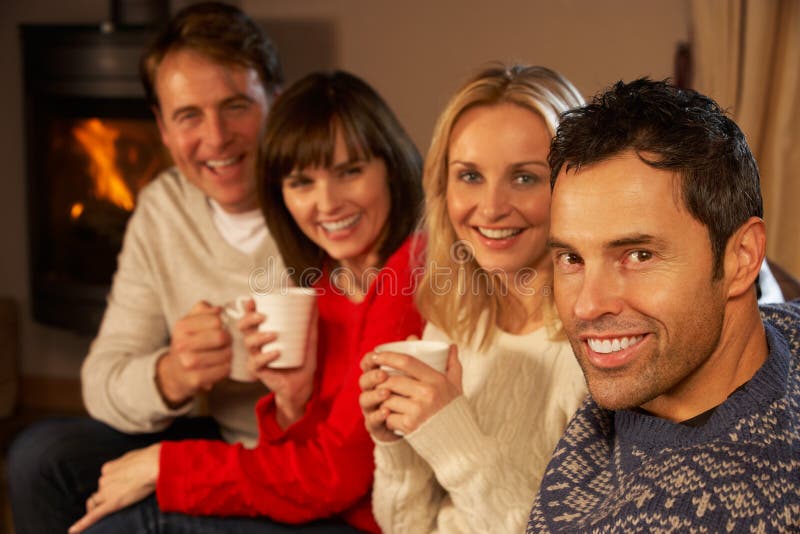 Group Of Middle Aged Couples Sitting On Sofa With Hot Drinks Talking. Group Of Middle Aged Couples Sitting On Sofa With Hot Drinks Talking