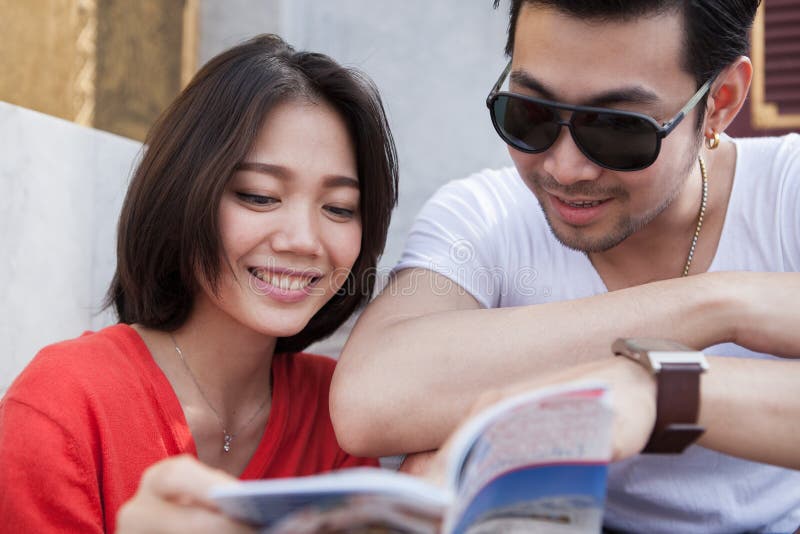 Paren van de Aziatische jongere reizende mens en vrouw die een gids lezen stock fotografie Paren van de Aziatische jongere reizende mens en vrouw die een gids lezen stock fotografie