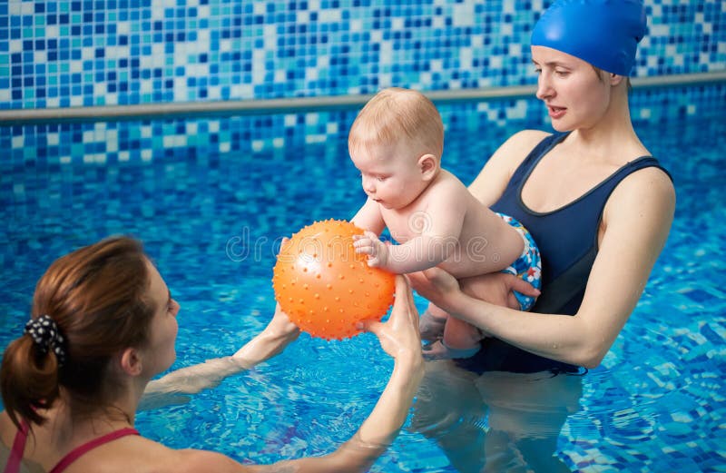 Parent and child having leisure time in swimming pool using inflatable toys for water fun. Child development. Side view