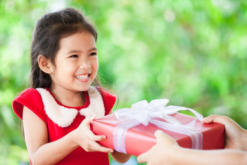 Parent a doação do presente do Natal à menina asiática bonito da criança fotografia de stock Parent a doação do presente do Natal à menina asiática bonito da criança fotografia de stock