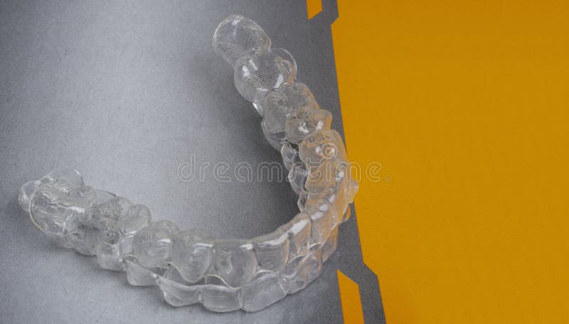 Parentesi dentali invisibili: dispositivi di allacciamento dei denti, supporti di plastica che mantengono i denti sullo sfondo gr immagine stock Parentesi dentali invisibili: dispositivi di allacciamento dei denti, supporti di plastica che mantengono i denti sullo sfondo gr immagine stock