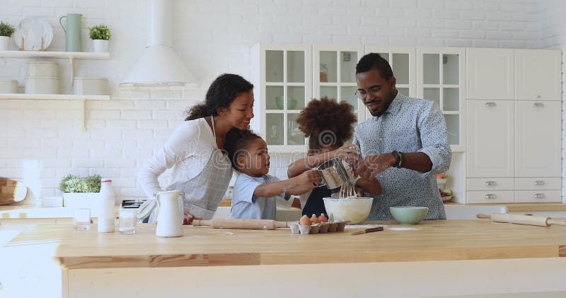 Parents africains heureux d'appartenance ethnique qui regardent la cuisson de frères et soeurs d'enfants.