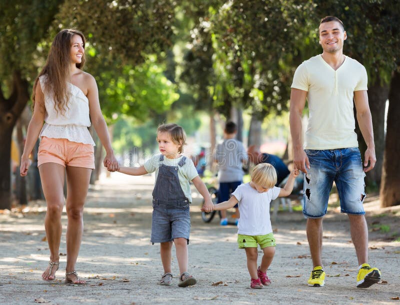 Parents avec deux petits enfants par le parc
