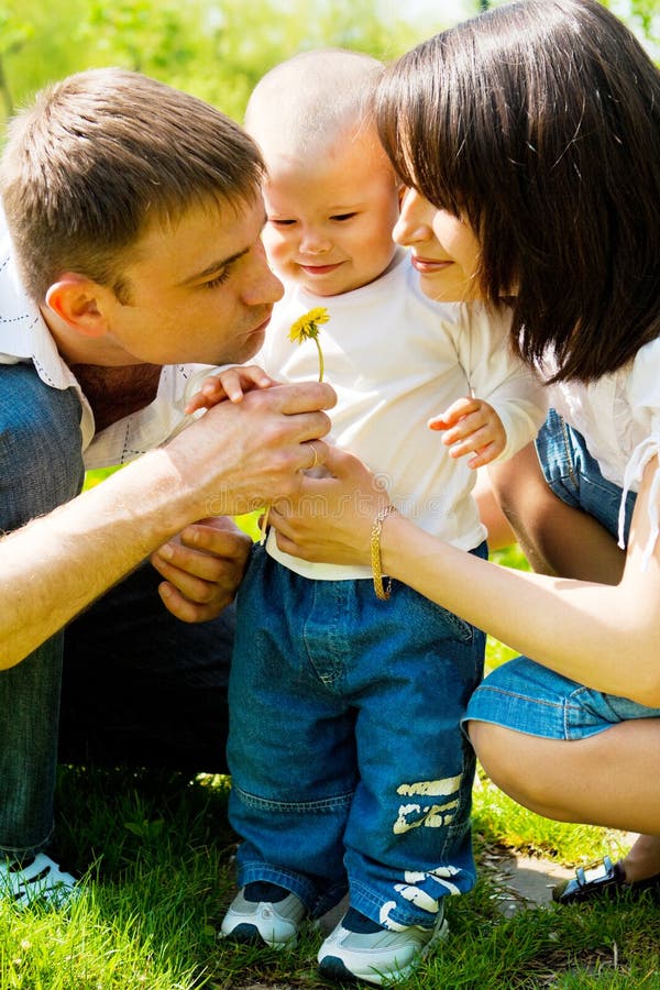 Parents showing dandelion to their baby. Parents showing dandelion to their baby