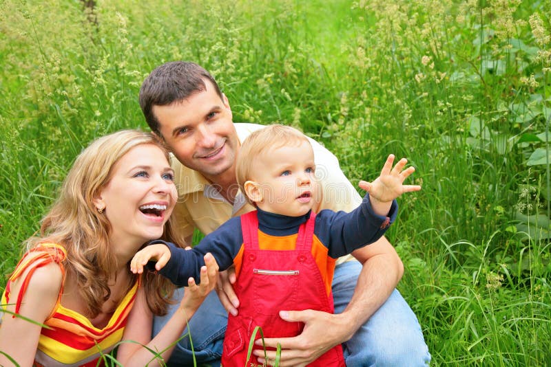 Parents with child sit in grass