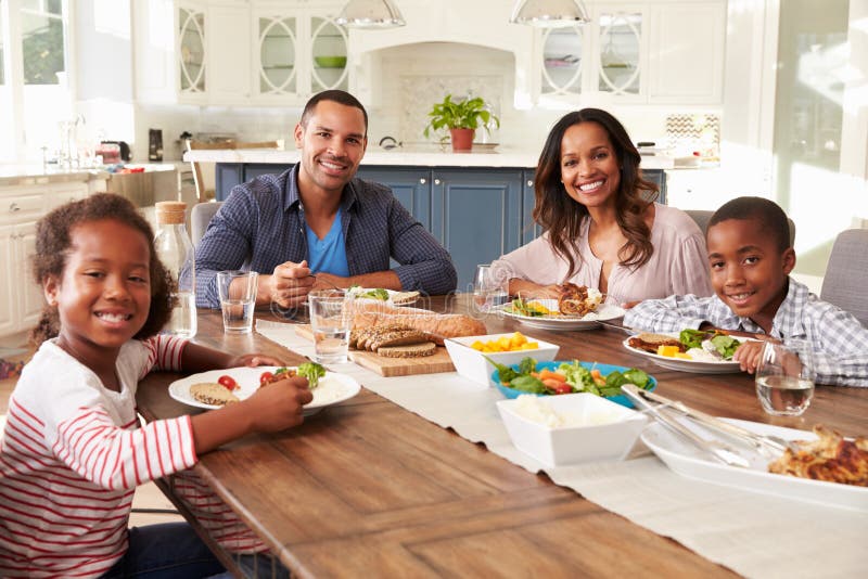 Parents and children eating at kitchen table look to camera royalty free stock photography Parents and children eating at kitchen table look to camera royalty free stock photography
