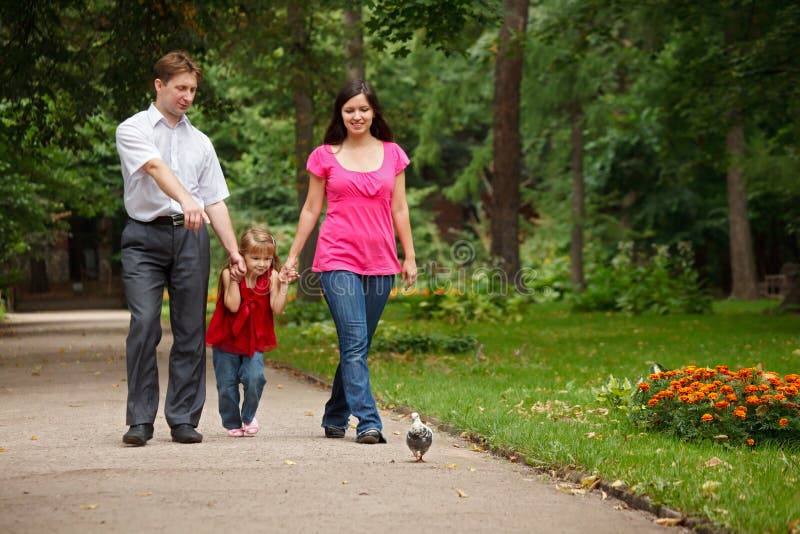 Parents with daughter walk on summer garden