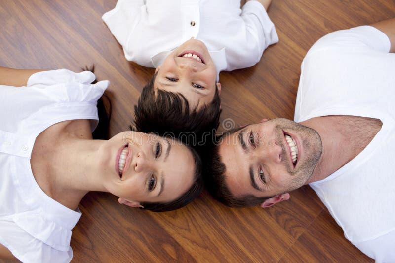 High angle of parents and kid lying on floor with heads together. High angle of parents and kid lying on floor with heads together