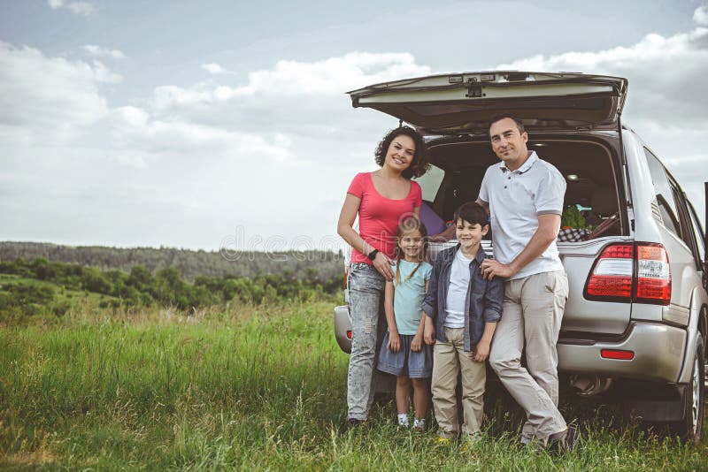 Parents gais et enfants détendant sur le pré image stock Parents gais et enfants détendant sur le pré image stock