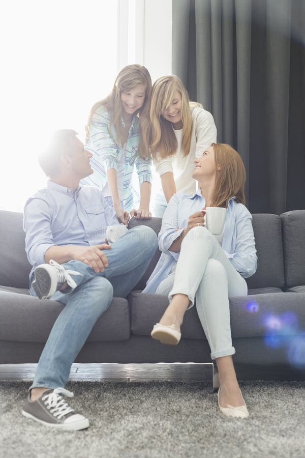 Parents heureux avec des filles passant le temps de qualité dans le salon photo stock Parents heureux avec des filles passant le temps de qualité dans le salon photo stock