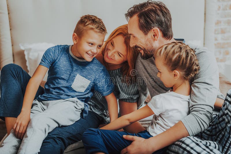 Parents heureux et deux enfants embrassant ensemble image stock Parents heureux et deux enfants embrassant ensemble image stock