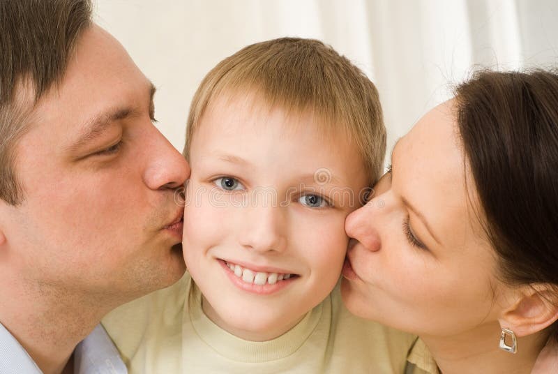 Parents kissing her child