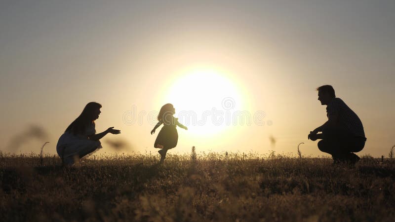 Parents play with their little daughter. mother and Dad play with their daughter in sun. happy baby goes from dad to mom. young family in field with a child 1 year. family happiness concept.