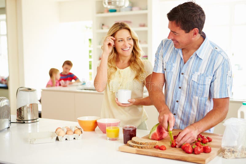 Parents préparant le petit déjeuner de famille dans la cuisine images stock Parents préparant le petit déjeuner de famille dans la cuisine images stock
