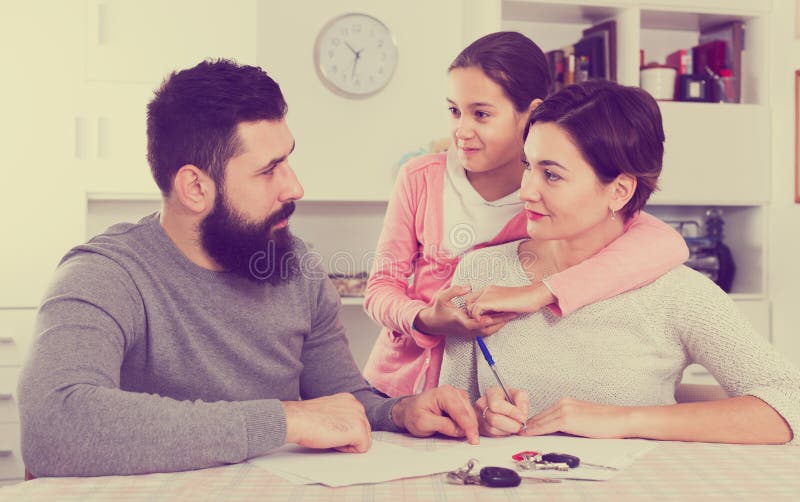 Young men and women signing papers for divorce while their daughter at home interior. Young men and women signing papers for divorce while their daughter at home interior