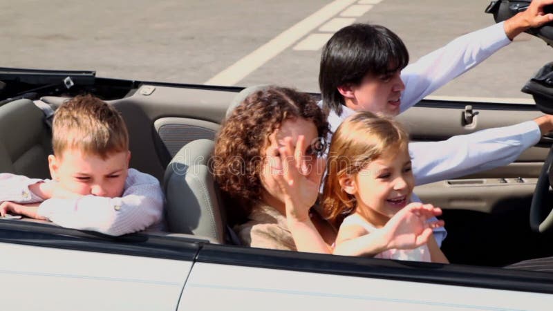 Parents and two kids pass by in cabriolet at sunny stock video footage