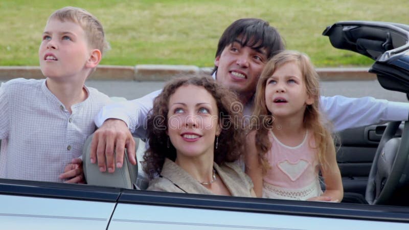 Parents and two kids sit in cabriolet and watch stock video