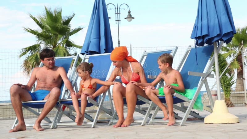 Parents and two kids are sitting in deckchairs stock video footage
