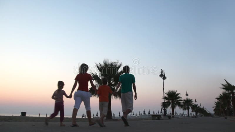 Parents and two kids are walking on waterfront stock video